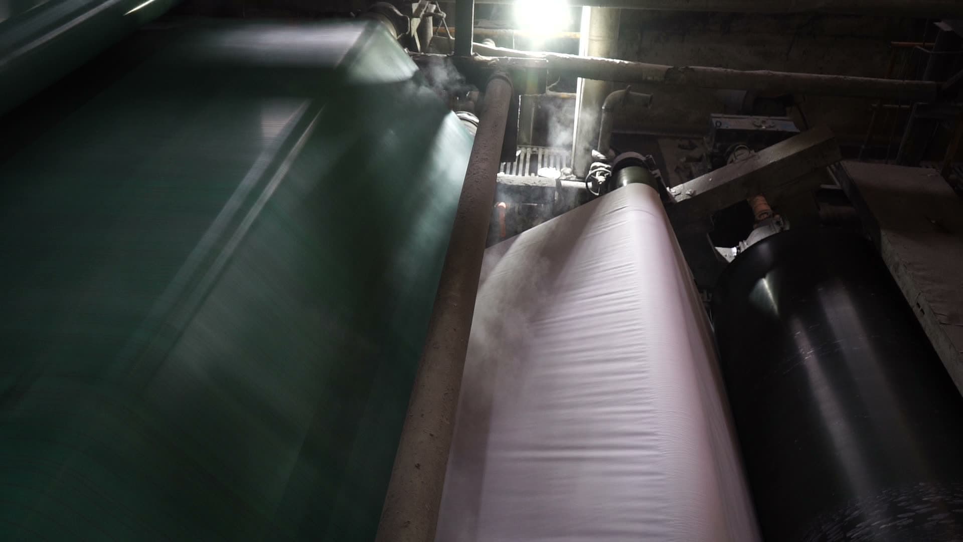 The paper web running over the dryer section, steam lifting off the sheet